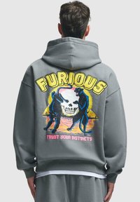 Grå hettegenser med dristige grafikker av to svarte pantere og et kranium, med teksten "FURIOUS" og "TRUST YOUR INSTINCTS" i sterke farger.