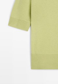 Maglione a maniche corte in tessuto knit verde chiaro, con orlo e maniche a coste, caratterizzato da una texture liscia e un design minimalista.