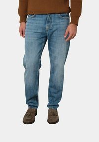 Jeans in denim azzurro chiaro con vestibilità a gamba dritta, cinque tasche e un leggero sbiadimento. Indossati con scarpe in suede marrone e un maglione in maglia marrone.