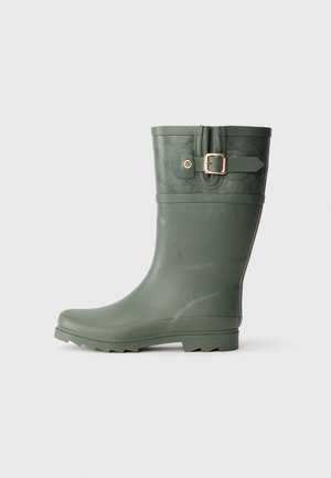 Botte de pluie en caoutchouc verte avec un bout rond, une tige texturée et un détail de boucle dorée sur le côté. Semelle antidérapante avec des crampons bien définis.