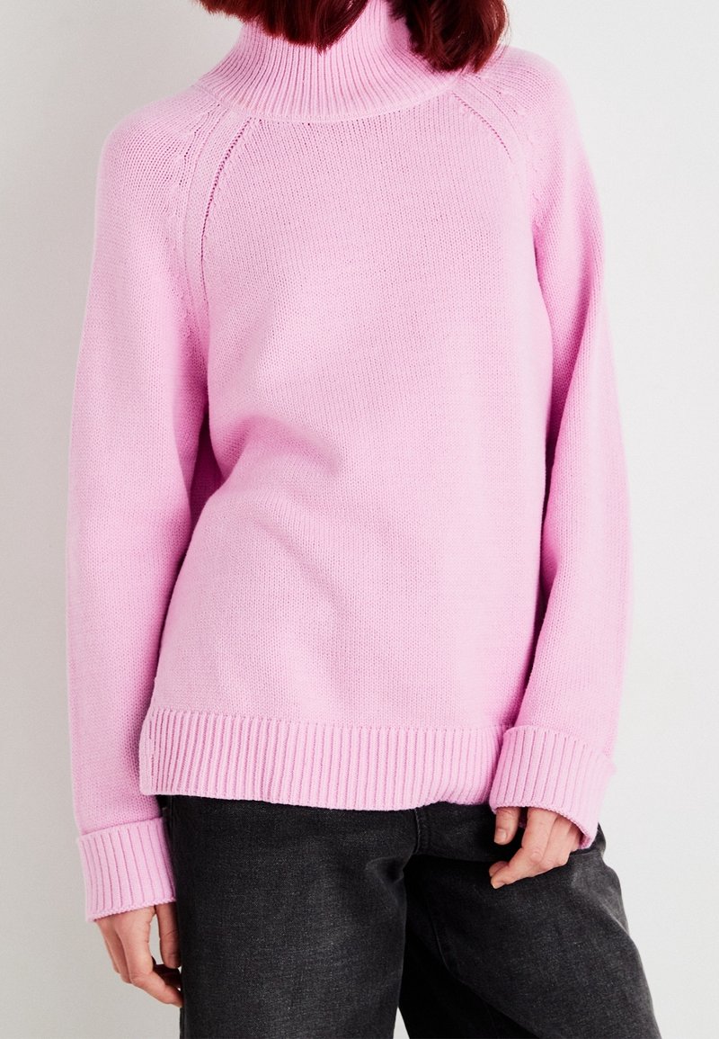 Pull en tricot rose avec un col montant côtelé, des poignets et un ourlet côtelés. Caractérisé par une coupe décontractée et une texture lisse, adapté pour un usage quotidien.