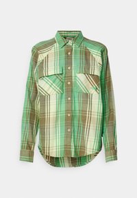 Zelená a hnědá kostkovaná košile na knoflíky se dvěma náprsními kapsami, zaobleným spodním lemem a límcem. Vyrobená z látky s měkkou texturou.