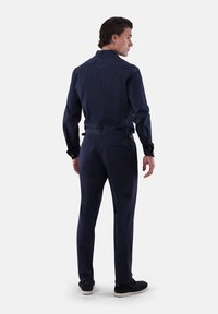 Marineblaues, maßgeschneidertes Hemd- und Hosen-Set. Verfügt über einen strukturierten Kragen, lange Ärmel und Gesäßtaschen. Glatter Stoff mit einem dezenten Schimmer.