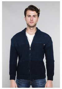 Marineblauer gestrickter Reißverschluss-Kardigan mit strukturiertem Muster, hohem Kragen und gerippten Bündchen. Verfügt über seitliche Taschen und dezente Logodetails.