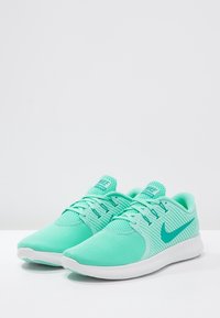 Scarpe da ginnastica verde menta con tomaia in rete testurizzata, lacci piatti e suola in gomma bianca con logo Nike turchese sul lato.