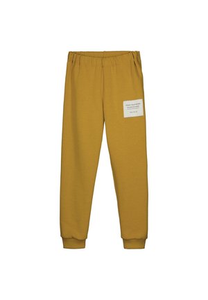 Pantalones jogger de color mostaza con cintura y puños elásticos, con un parche blanco con texto en el muslo derecho.
