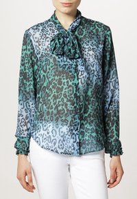Blusa trasparente con una sfumatura di stampa leopardata in teal e blu, caratterizzata da un colletto a fiocco, chiusura con bottoni e polsini arricciati.