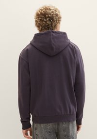 Dunkelviolette Kapuzenjacke mit Kordelzug, gerippten Säumen und einem gerippten Bund. Weiche Stoffstruktur, von hinten betrachtet, mit einem schlichten Design.