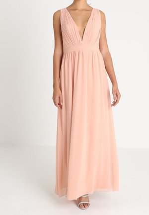 Różowa, miękka, bezrękawnikowa sukienka maxi z głębokim dekoltem w serek, plisowanym gorsetem i zwiewną spódnicą, noszona z srebrnymi sandałami na otwartym palcu.