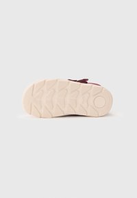 Sola de sapatilha em cor bordeaux com um fundo de borracha branca texturizada, apresentando um padrão em zig-zag e acentos arredondados para melhor aderência e durabilidade.