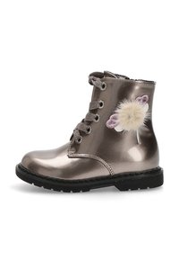 Botín de tobillo metálico bronce con diseño de cordones, que presenta un pom-pom blanco esponjoso y un acento floral. Suela de goma negra.