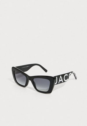 Black oversized square sunglasses with gradient lenses and white "JACOB" lettering on the temples, set against a plain light background.