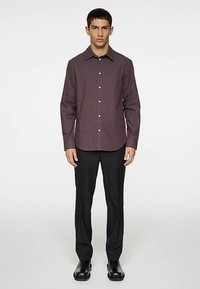 Camisa de cor castanho-avermelhado com botões, gola, mangas compridas e textura subtil, combinada com calças pretas e sapatos pretos. Design simples e ajustado.