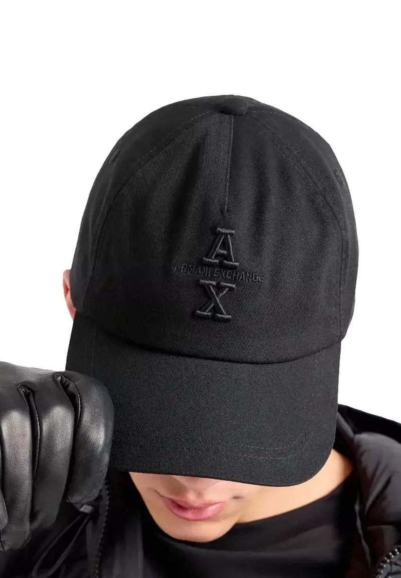 Casquette de baseball noire en coton avec un logo "AX" brodé sur le devant, dotée d'un bord incurvé et d'une couronne structurée.