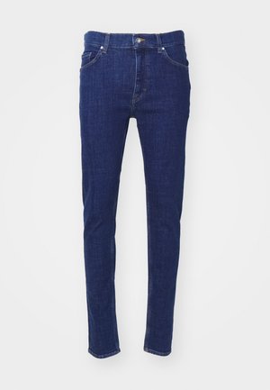 Tamno plave traperice s uskim krojem. Imaju pet džepova, zatvaranje na gumb i šivane detalje uz šavove. Glatka tekstura.