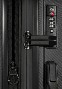 Valise rigide noire avec une section de fermeture éclair dotée de doubles serrures, d'un cadran à combinaison et d'une surface texturée portant le nom "REDOLZ."