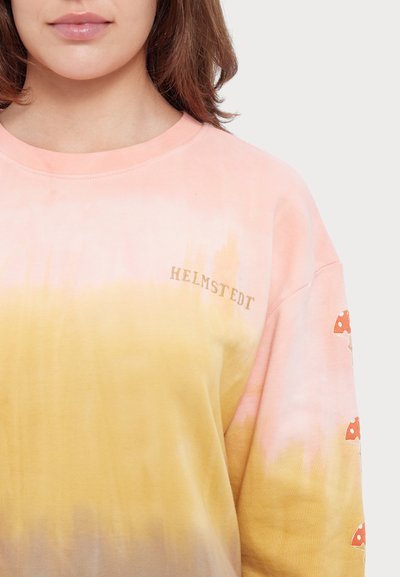 Pika-särgi, millel on pikad varrukad ja tie-dye mustriga gradient roosast kollasele. "HELMSTEDT" logo kuldse värviga ja punased seenemotiivid varrukatel.