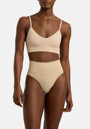 Nude bralette en set van high-waisted slip; naadloos ontwerp, zachte stof, verstelbare banden, glanzende textuur, minimalistische stijl zonder zichtbare hardware.