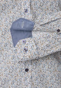 Button-up shirt in a light fabric featuring a floral pattern in blue and brown, with a solid blue cuff and contrasting blue buttons.