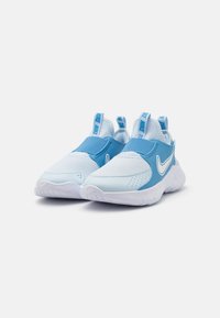 Baskets de sport bleu clair avec une tige en mesh, une sangle bleue contrastante, un swoosh Nike blanc et une semelle en caoutchouc texturé. Deux languettes à l'arrière.
