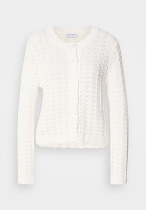 Cárdigan blanco de punto con un patrón texturizado, cuello redondeado y bordes con ondas. Cuenta con cinco botones en el frente.