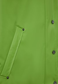 Ryškiai žalia vandeniui atspari striukė pasižymi elegantišku dizainu, lygiu paviršiumi, šonine kišene ir juodais mygtukais uždarymui.