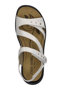 White leather sandal with three crossed straps, padded insole featuring leaf design, and black rubber outsole. Adjustable buckle on the side.