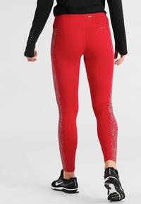 Czerwone legginsy sportowe z wysokim stanem, z teksturowanym gradientowym wzorem po bokach. Wykonane z elastycznego, odprowadzającego wilgoć materiału.