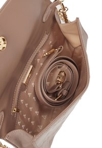 Beige laukku, joka on valmistettu sileästä nahasta. Siinä on kultapronssinen kiinnitys, vuorattu sisustus, jossa on kuvio, ja irrotettava hihna.