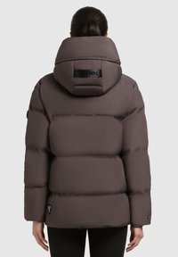 Puffet brun vinterjakke med en stor hætte og prægede logo på ryggen. Funktioner inkluderer en glat tekstur og tætsiddende ærmer.