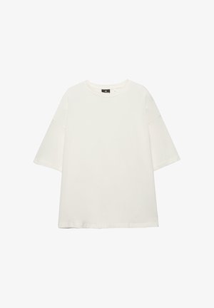 Fehér, bő szabású, rövid ujjú környakú póló, laza fazonú és minimalista dizájnnal, fehér háttéren letéve.