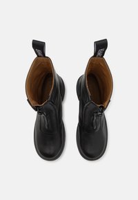 Black leather ankle boots with a smooth finish, featuring a zip closure and contrasting brown interior, and pull tabs for easy wearing.