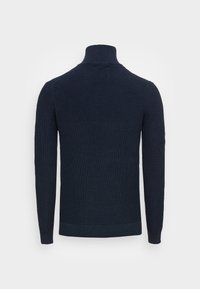 Marineblå strikket sweater med høj krave, ribbet tekstur, lange ærmer og en tætsiddende kant, der viser en ensfarvet farve uden mønstre.