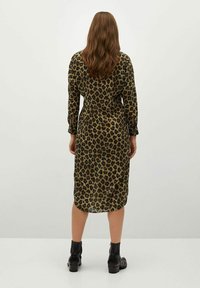 Leopardi-kuosiset pitkähiharat mekko, valmistettu kevyestä kankaasta, keskipitkä leikkaus ja yhdistetty mustiin nilkkasaappaisiin.