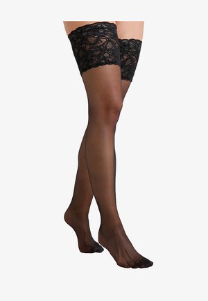 Des bas hauts en dentelle noire avec une texture lisse et transparente et une couture subtile courant le long de l'arrière jusqu'à l'orteil.