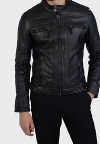 Musta nahkainen moottoripyörätakki, jossa on korkea kaulus, vetoketjullinen etuosa ja useita vetoketjullisia taskuja. Sileä rakenne ja istuva malli.