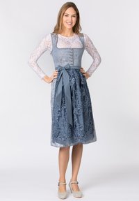 Blaues besticktes Kleid mit einer Spitzenüberlagerung, einem taillierten Oberteil, Knöpfen und einem gebundenen Taillengürtel. Kombiniert mit grauen Plateau-Heels.