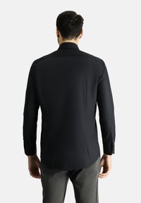 Camicia nera a maniche lunghe con colletto standard, tessuto morbido e design dritto sul retro. Presenta polsini con bottoni e orlo curvo.