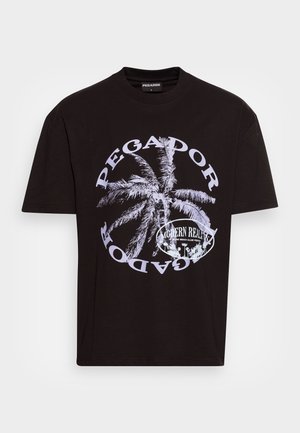 Sort bomuld T-shirt med stort hvidt palmetræsgrafik, cirkulær tekst "PEGADOR" og "MODERN REALITY," korte ærmer, afslappet pasform.