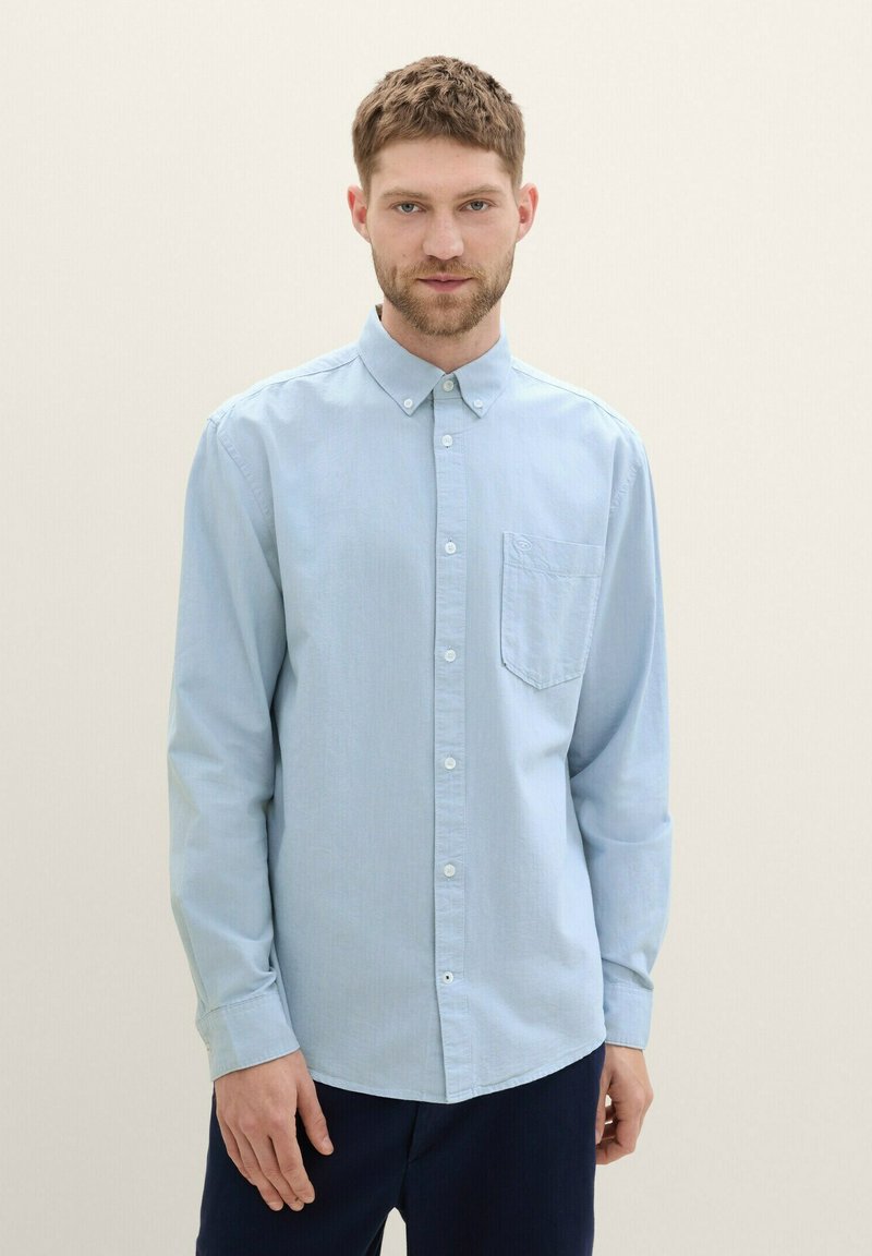 Light blue button-up shirt with long sleeves, a collared neck, a chest pocket, and subtle texture; fabric appears soft and slightly shiny.