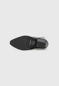 Black leather ankle boot featuring a rounded toe, smooth texture, low block heel, and patterned rubber sole with branding detail.