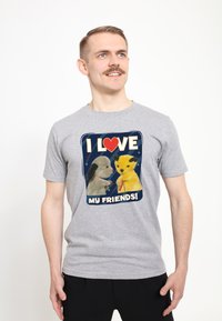 Šedé bavlněné tričko s grafickým motivem dvou plyšových postaviček a textem "MILUJI SVÉ PŘÁTELE!" na tmavě modrém pozadí.