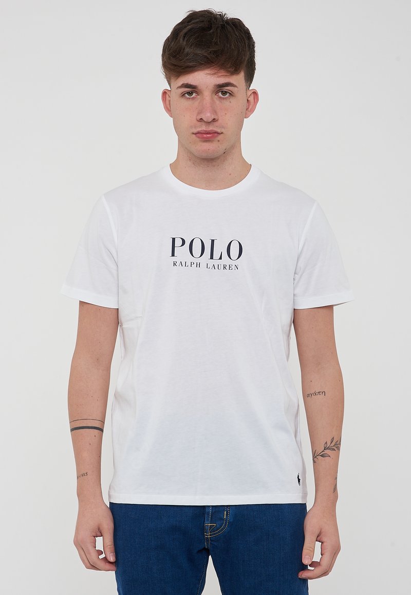 T-shirt bianco in cotone con la scritta "POLO RALPH LAUREN" stampata in blu navy. Collo tondo, maniche corte, con un piccolo logo sull'orlo.