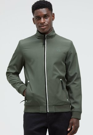Olive green jacket with a high collar, front zipper, and white accents, featuring side pockets and ribbed cuffs and hem.