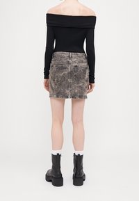 Czarny prążkowany top bez ramiączek w połączeniu z wyblakłą dżinsową spódnicą mini. Spódnica posiada dwie tylne kieszenie oraz postarzany wygląd. Czarne botki.