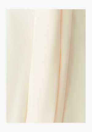 Svijetlo bež tkanina elegantno pada, s glatkom teksturom i lagano prozirnom kvalitetom. Materijal djeluje mekan i tečan.