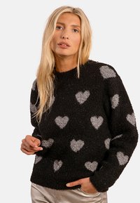 Maglione nero con finitura testurizzata, caratterizzato da un motivo di cuori grigi. Collo rotondo e maniche lunghe, materiale morbido. Design minimalistico.