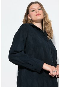 Camicia nera, con texture, a maniche lunghe e colletto; tessuto morbido, con un fit rilassato e polsini con bottone.