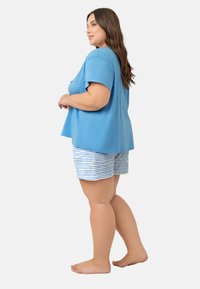 Niebieska bawełniana koszulka z krótkim rękawem w zestawie z paskowanymi szortami w niebiesko-białe paski. Strój ma luźny krój i miękką teksturę.