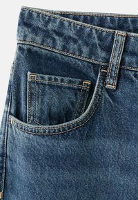 Vaqueros de mezclilla en azul oscuro con una textura suave. Presentan un bolsillo frontal, costuras visibles y una cinturilla resistente.